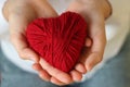 Children`s hands hold a heart of red thread for knitting. Valent