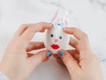 Children& x27;s hands hold one white egg with glued eyes, lips, bow tie and glue paper bunny ears