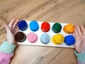 Children's hands hold a tablet with colorful wooden houses. Montessori method.