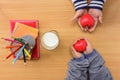Children`s hands holding red heart and notebook with color pencil and milk on wood en table. Royalty Free Stock Photo