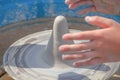 Children`s hands and piece of crude clay on potter`s wheel