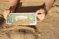 Children`s hands pull a bill of one dollar from the sea sand. A finding on vacation. Finance, sea, vacation Royalty Free Stock Photo
