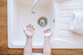 Children's hands in soapy foam over a light sink. View from above. Hygiene and healthcare concept