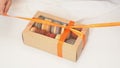 Children`s hands untie bow on gift box with macarons