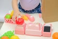 Children`s hands weighs tomatoes on scales, little girl plays in children`s store at home with plastic toys, toy cash register, Royalty Free Stock Photo