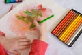 Children`s hands on a white table drawing Christmas tree with olorecd pencils. Drawing a Christmas tree with pencils