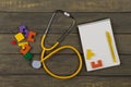 Children's healthy development concept - blank notepad, yellow stethoscope, colorful wooden jigsaw puzzles