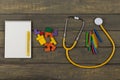 Children's healthy development concept - blank notepad, yellow stethoscope, colorful wooden jigsaw puzzles, crayons