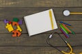 Children's healthy development concept - blank notepad, yellow stethoscope, colorful wooden jigsaw puzzles, crayons