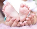 Children`s legs in the hands of the mother. Tiny legs of a newborn baby on female hands close-up. Mom and her baby. The concept o Royalty Free Stock Photo