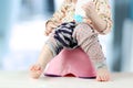 Children's legs hanging down from a chamber-pot on a blue backgr