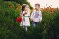Children`s love, a little boy and a girl, amicably spend time, laugh and smile, and kiss in the flowering field of poppies