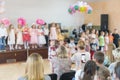 Children's party in primary school. Young children on stage in kindergarten appear in front parents. blurry