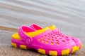 Children`s pink clogs stand on a sandy beach near the water. Royalty Free Stock Photo