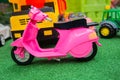 Children`s pink motorcycle stands against the background of other toys.