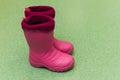 Children`s pink rubber boots on the green floor. children`s rain shoes. Royalty Free Stock Photo