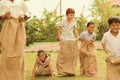 Children`s playing potato sack jumping race at park outdoor - kids falling and having fun while playing gunny sack race. Royalty Free Stock Photo