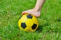 Children's shoeless foot and a soccer ball on green grass