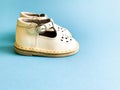 Children`s shoes, the concept of the first step. Baby white on a blue colored background. Space for the text. The first steps of t