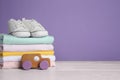 Children`s shoes, stack of clothes and toy on white wooden table. Space for text Royalty Free Stock Photo