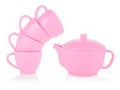 Children`s small mugs and a pink teapot stand on top of each other on a white background. Toy set made of plastic. The concept of Royalty Free Stock Photo