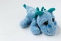 Children`s soft toy blue dragon is located on a white background