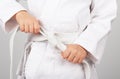 Children`s sports. Karate. Children`s hands tying white karate kimono belt