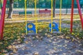 Children`s swing on the playground. Yellow leaves in the playground. Gold autumn. Yellow leaves are scattered on the playground o