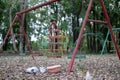 Children`s swings hang empty an idle at a playground on a dull, overcast day. Lost child day Royalty Free Stock Photo