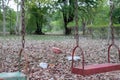 Children`s swings hang empty an idle at a playground on a dull, overcast day. Lost child day Royalty Free Stock Photo