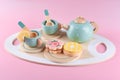 Children`s tea set, fake cake and biscuit, wooden kitchenware. Cute kids toys to play in the kitchen, blue cups with teapot.