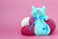 Children`s toy cat made of felt on a colored background next to the balls of yarn Royalty Free Stock Photo