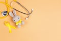 Children`s toy with a Childhood Cancer Awareness Golden Ribbon and stethoscope on yellow background with copy space