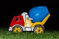 Children`s toy concrete mixer. Colored plastic baby car on grass background. Car Models. Kids toys. Closeup. At night Royalty Free Stock Photo