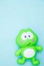 Children`s toy funny green frog close-up, isolated on a blue background. macro