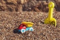 Children`s toy truck with gravel or sand. Yellow scoop on the background. Concept of transportation of goods and