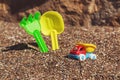 Children`s toy truck with gravel or sand. Yellow scoop and green rake on the background. Concept of transportation of Royalty Free Stock Photo