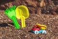 Children`s toy truck with gravel or sand. Yellow scoop and green rake on the background. Concept of transportation of Royalty Free Stock Photo