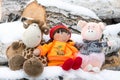 Children`s toys giraffe, doll, pig sitting in the snow on birch wood