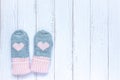 Children`s winter accessories, warm knitted mittens - gray with pink hearts on white wooden background. Flat lay, copy Royalty Free Stock Photo