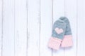 Children`s winter accessories, warm knitted mittens - gray with pink hearts on white wooden background. Flat lay, copy Royalty Free Stock Photo