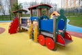 A children`s wooden train with a red blue yellow trailer on a yellow playground in the city. Playgrounds Royalty Free Stock Photo