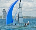 Children sailing racing small sailboat with a blue spinnaker on a coastal lake. Commercial use photo