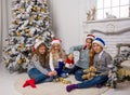 Children in Santa caps are decorate a Christmas tree in a room. Royalty Free Stock Photo