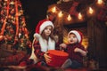 Children in Santa's hats open giftbox near fireplace and christmas tree. New Year concept Royalty Free Stock Photo