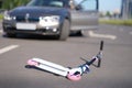 Children scooter lying on road near car closeup