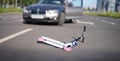 Children scooter lying on road near car closeup