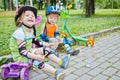 Children scooterists rest sitting on curb of Royalty Free Stock Photo