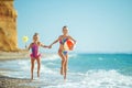 Children at sea play merrily. Two sisters run, jump on the beach in summer. Royalty Free Stock Photo