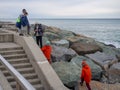 Children on the seashore in winter. Teenagers play on the rocky shore. At the resort in winter